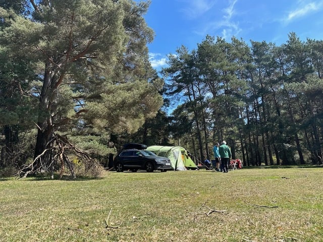A family stood next to pitched up tent at Roundhill Campsite in the New Forest.