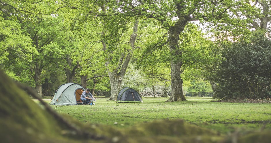 A man sat out front of two tents in the New Forest.
