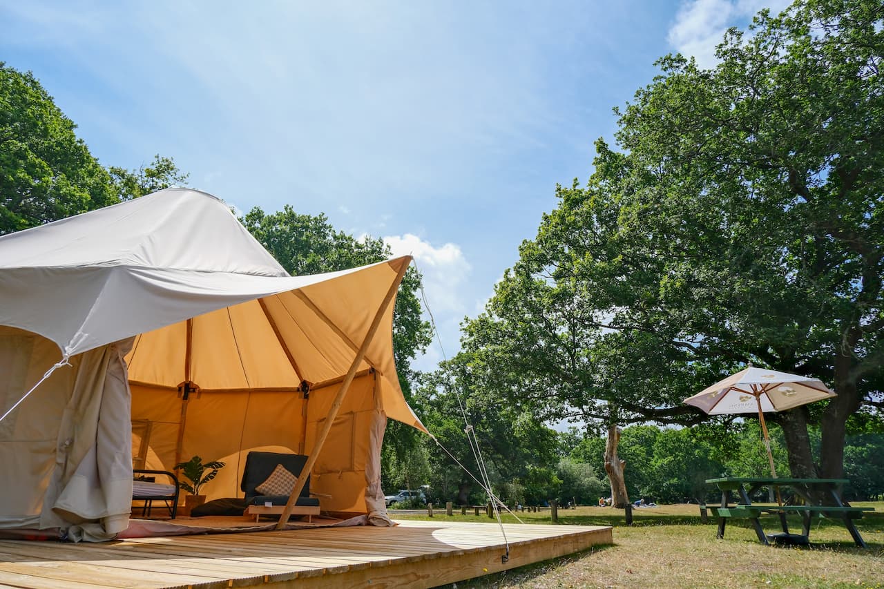 Burt tent glamping accommodation with decking and outdoor seating in the New Forest, Ashurst Campsite